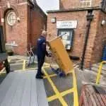 Removal specialist using tilt trolley to safely move large furniture during house removal